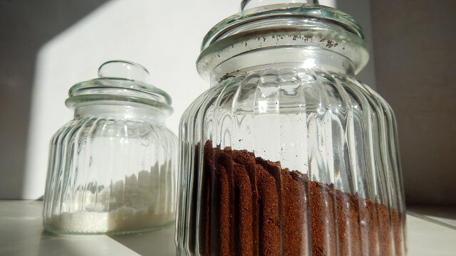 two glass jars with ground coffee and sugar on the table