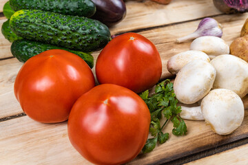 cucumbers, tomatoes, porcini mushrooms and parsley on a wooden background.