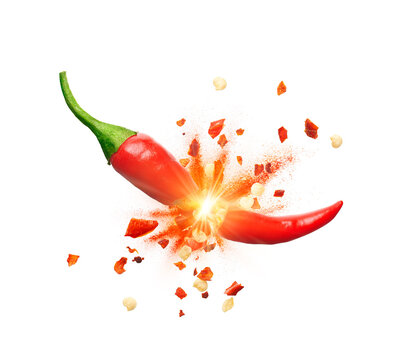 Chili powder and chili flakes burst out from red chili pepper over white background