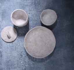 Empty white clay dishes on blue background. Handmade plate and bowls, top view.
