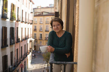 lifestyle portrait of cheerful mature and healthy woman 60 to 65 years old relaxed on home balcony...