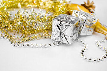New year decorations - silver little gifts, shiny golden tinsel, yellow toys, beads on a white background. Christmas concept.