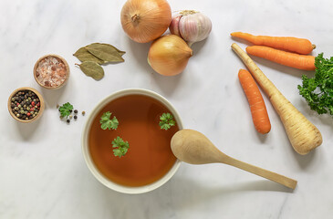 Flat lay of homemade beef bone broth in a bowl with ingredients. Contains minerals and healthy...