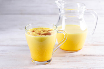 Traditional indian drink turmeric golden milk in a glass on a wooden table