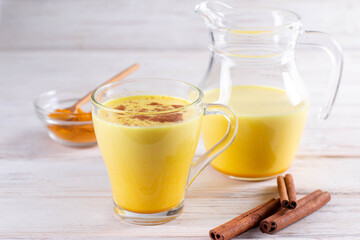 Hot healthy drink. Turmeric latte, golden milk with turmeric root, ginger powder on a white background. Spices for ayurvedic treatment. Alternative medicine concept