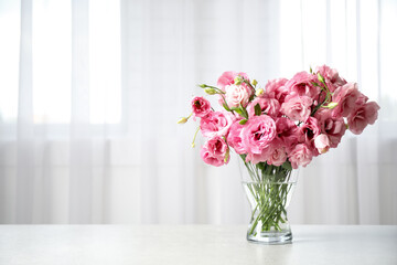 Beautiful pink Eustoma flowers in vase on table indoors. Space for text