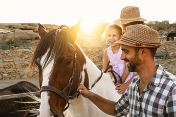 Happy family having fun riding on horse inside ranch - obrazy, fototapety, plakaty
