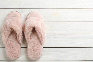 Pair of stylish soft slippers on white wooden background, flat lay. Space for text