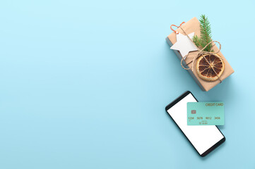 Christmas online shopping concept. Top view of smartphone, credit card and gift box on pastel blue background. flat lay, copy space