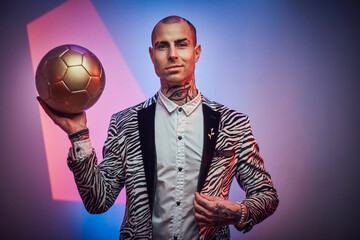 Positive and succesful football trainer dressed in custom suit with jewellery poses with golden...