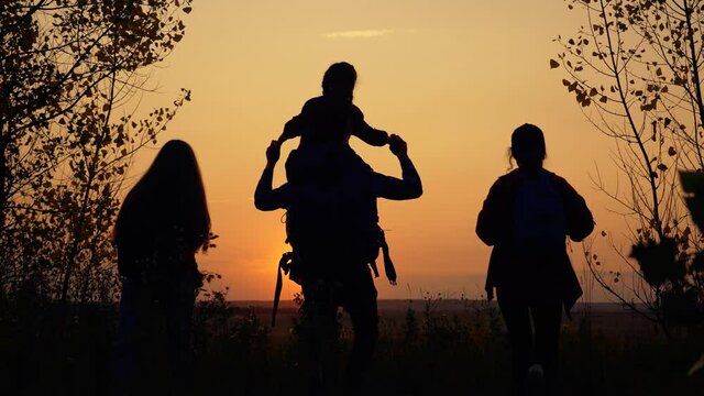Tourists teamwork. Happy family in the park. Hiker hiking climbing. Happy family of tourists with backpacks going hiking. Silhouette group of tourists in the park at sunset.Teamwork on Hiking.