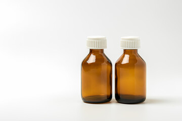 Glass containers for medicines on a white background. Two empty brown pharmaceutical bottles without labels