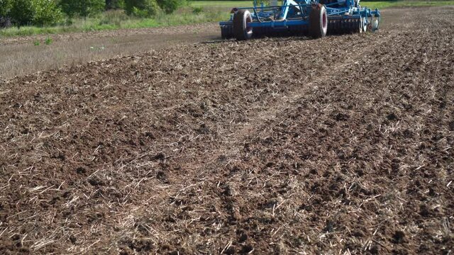 Tractor discing stubble field with special equipment cultivating farm land soil