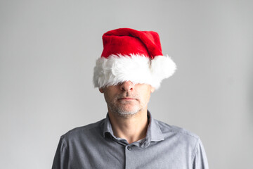 Portrait eines Mannes mit einer roten Weihnachtsmütze über den Augen. Humor, Hemd, neutraler...