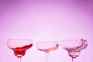 splashes cocktails at bright purple background 