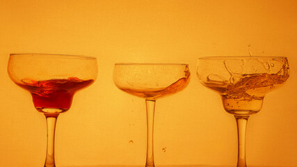 splashes cocktails at bright orange background 