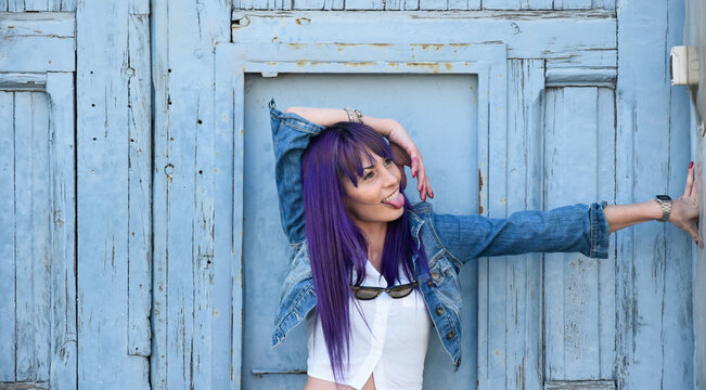 Chica guapa sacando la lengua sonriente con cabello lila