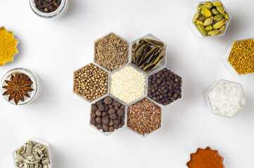 Spices in hexagonal jars on a white background