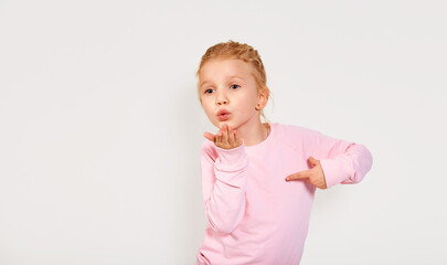 Cute 4-5 year old little girl sending a kiss. Isolated white background. Emotions close-up, lips bow. Kissing in pink clothes face expression.
