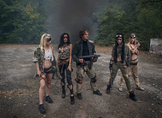 A group of young people in tattered clothes after the apocalypse. Smoke, grunge, chains, aggressive combat makeup