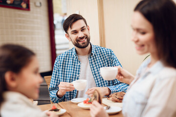 Young Happy Family Eating Cakes in Cafeteria.