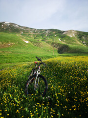 Fototapeta na wymiar In the mountains, green meadows and a bike, yellow flowers, blue sky 