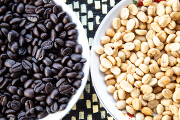 Dry group of black and white coffee bean in a white bowl.