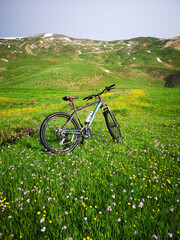 Fototapeta na wymiar In the mountains, green meadows and a bike, yellow flowers, blue sky 
