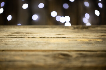Pusty stół drewniany z rozmytym tłem ze światełkami i lampkami o ciepłej barwie na święta