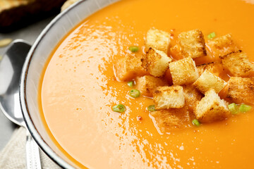 Tasty creamy pumpkin soup with croutons in bowl on table, closeup