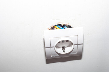 Broken electric socket torn from white wall