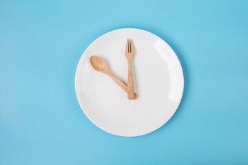 Top view white ceramic plate with knife, spoon and fork on blue background. Intermittent fasting, Ketogenic dieting, weight loss, meal plan and healthy food concept