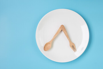 Top view white ceramic plate with knife, spoon and fork on blue background. Intermittent fasting, Ketogenic dieting, weight loss, meal plan and healthy food concept