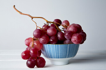 still life of red grapes on white wooden table