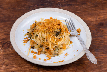 Spaghetti alla carrettiera, pasta with onions and breadcrumbs in a plate on a rustic wooden table