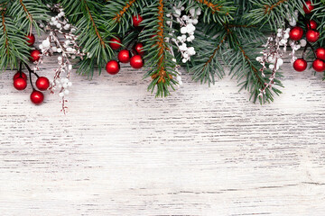 Christmas frame made of fir tree branches,white twigs, red berries and cones on the white wooden rustic background.Christmas background.Copy space for text, top view,flat lay