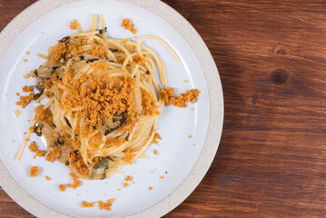 Spaghetti alla carrettiera, pasta with onions and breadcrumbs in a plate close-up on a rustic wooden table, top view, copy space