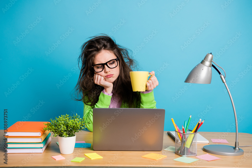 Poster i need more coffee. exhausted girl sit desk work remote look hold caffeine beverage mug isolated blu