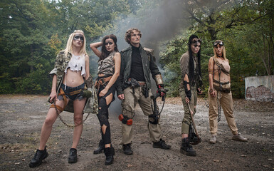 A group of young people in tattered clothes after the apocalypse. Smoke, grunge, chains, aggressive combat makeup