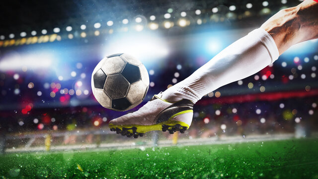 Fototapeta Football scene at night match with close up of a soccer shoe hitting the ball with power