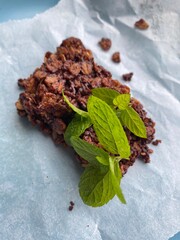 HOMEMADE ORGANIC CHOCOLATE FLAPJACK BISCUIT & CRUMBS WITH FRESH MINT LEAVES ON BAKING PAPER .