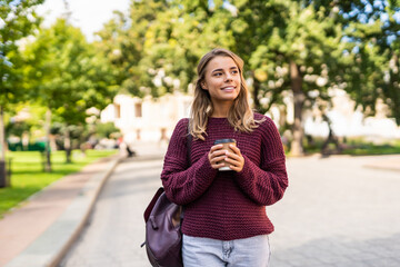 Young woman drinking coffee while walking on the street