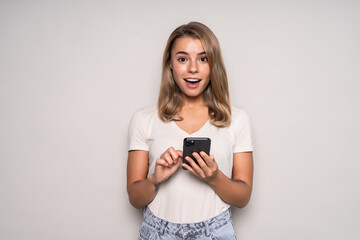 Beautiful woman sending a message with a mobile phone in a white isolated background
