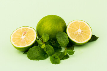 Lime with mint leaves isolated on light green background.