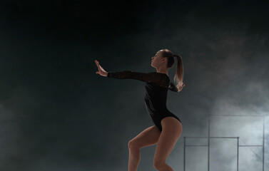 Fototapeta na wymiar Female gymnast doing a complicated trick in a professional arena.