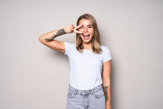 Portrait of happy cheerful woman showing peace gesture isolated over white background