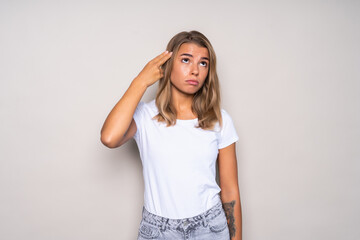 Depressed woman. Displeased young woman holding her hand like a gun near head and looking away while isolated on white background