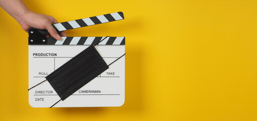 Hand is hold black Clapper board or movie slate with black face mask. it use in video production...