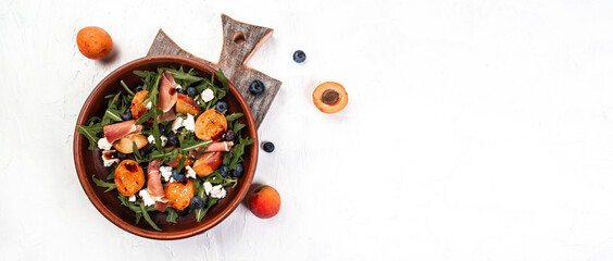 Gourmet salad with blue cheese, peaches, jamon ham and arugula on a light background, Flat lay. Banner. Top view