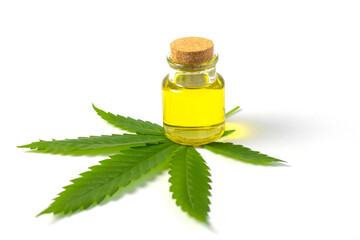 A small vial or glass jar with hemp oil stands on a marijuana leaf on a white background. Alternative medicine, skin care cosmetics with vegetable oils